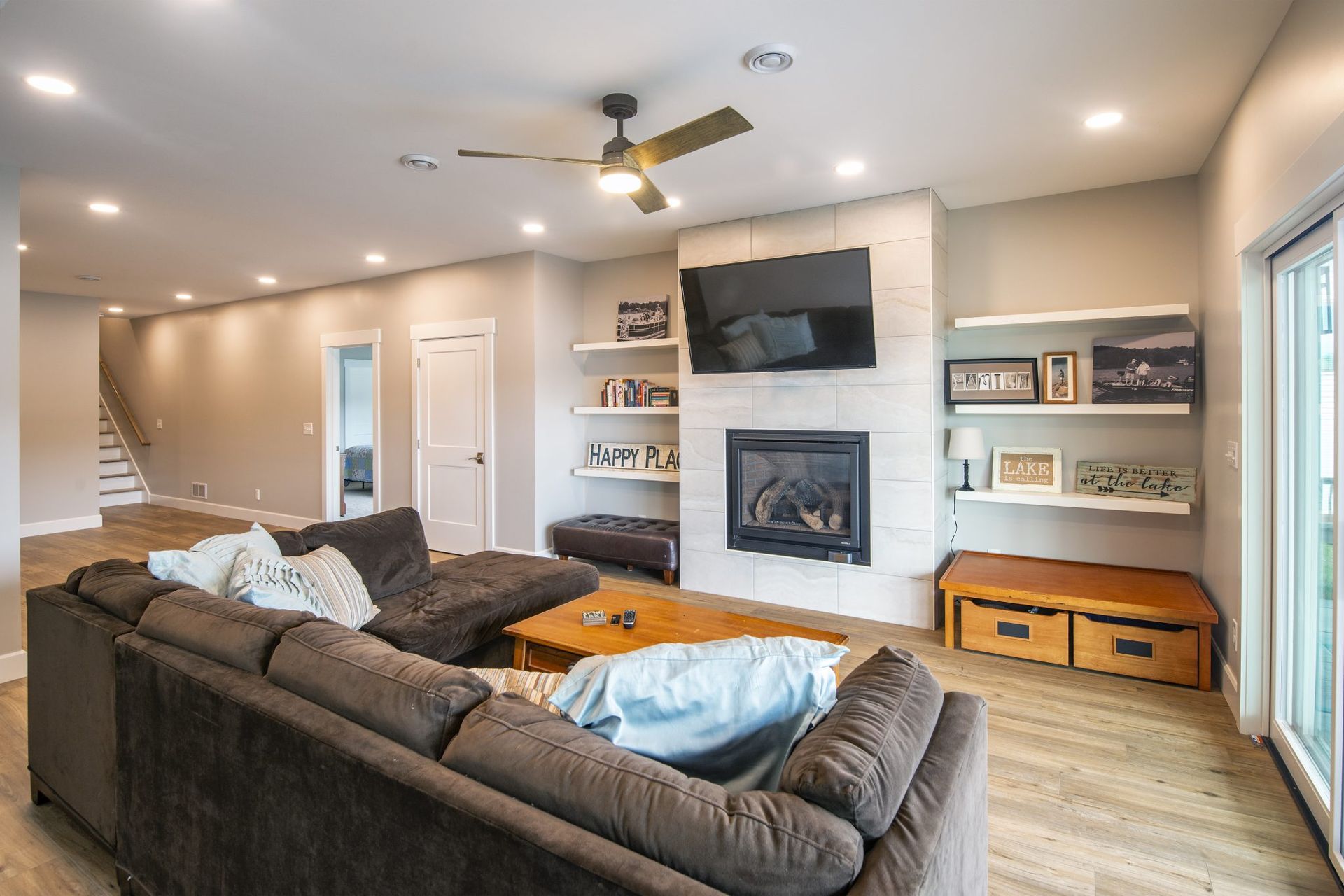 A living room with a couch, fireplace, television, and ceiling fan.