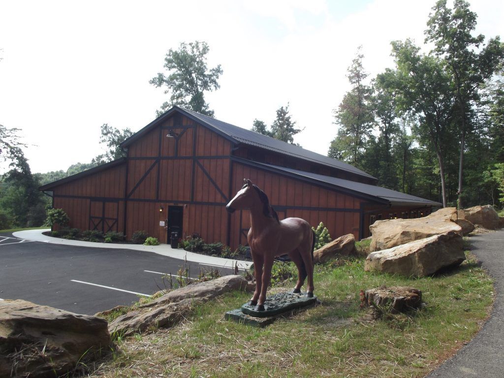 A statue of a horse in front of a barn style building.