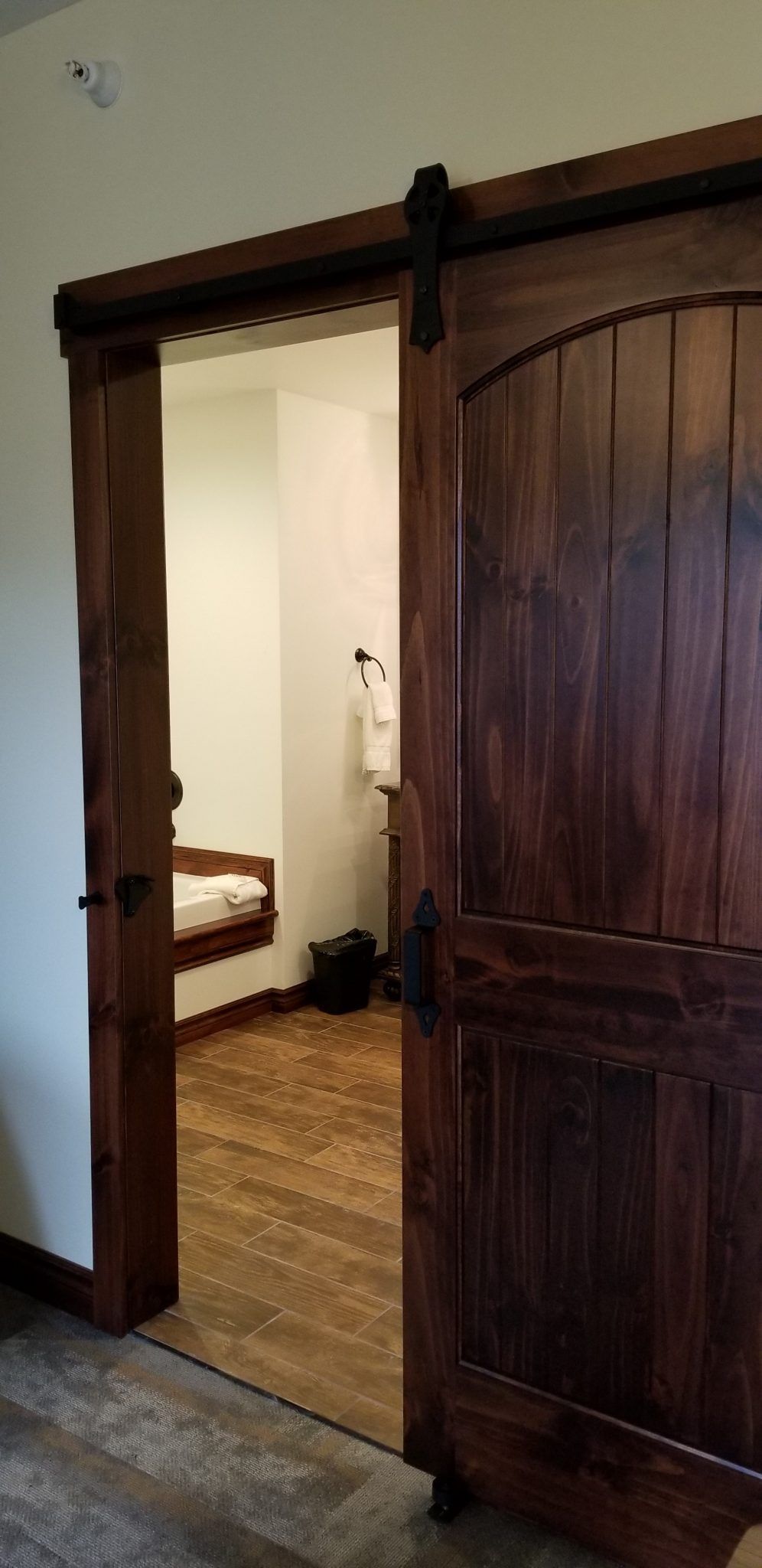 A wooden sliding barn door is open to a bedroom.