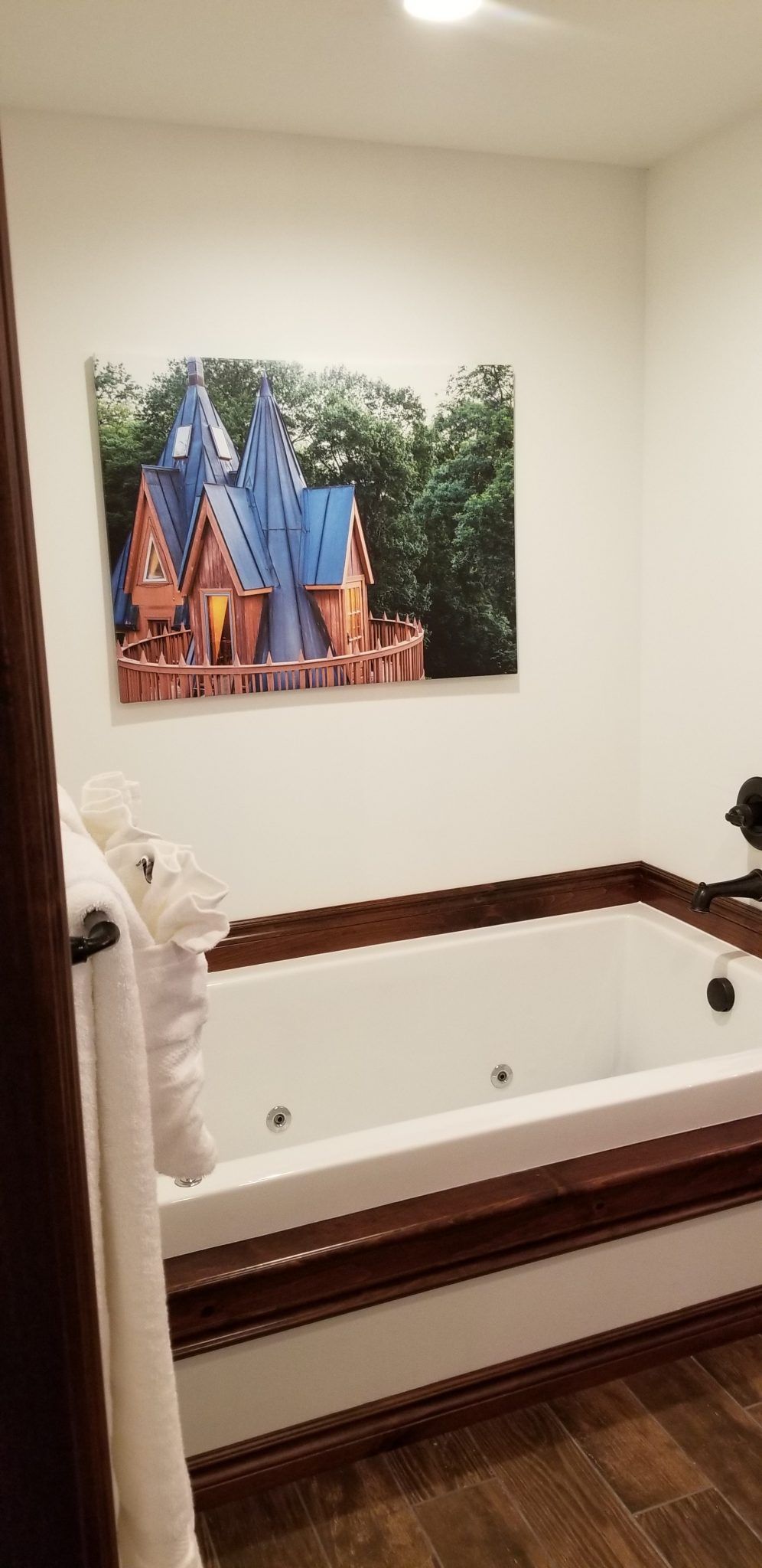 A bathroom with a jacuzzi tub and a picture of a castle on the wall.