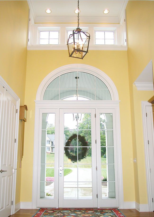 A door with a wreath on it and a chandelier hanging from the ceiling.