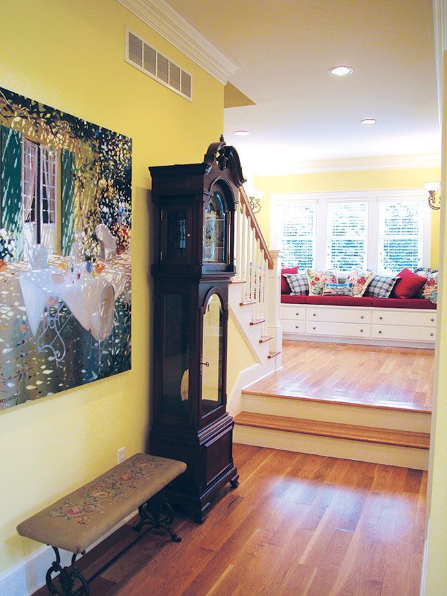 A large grandfather clock sits in a hallway next to a bench.