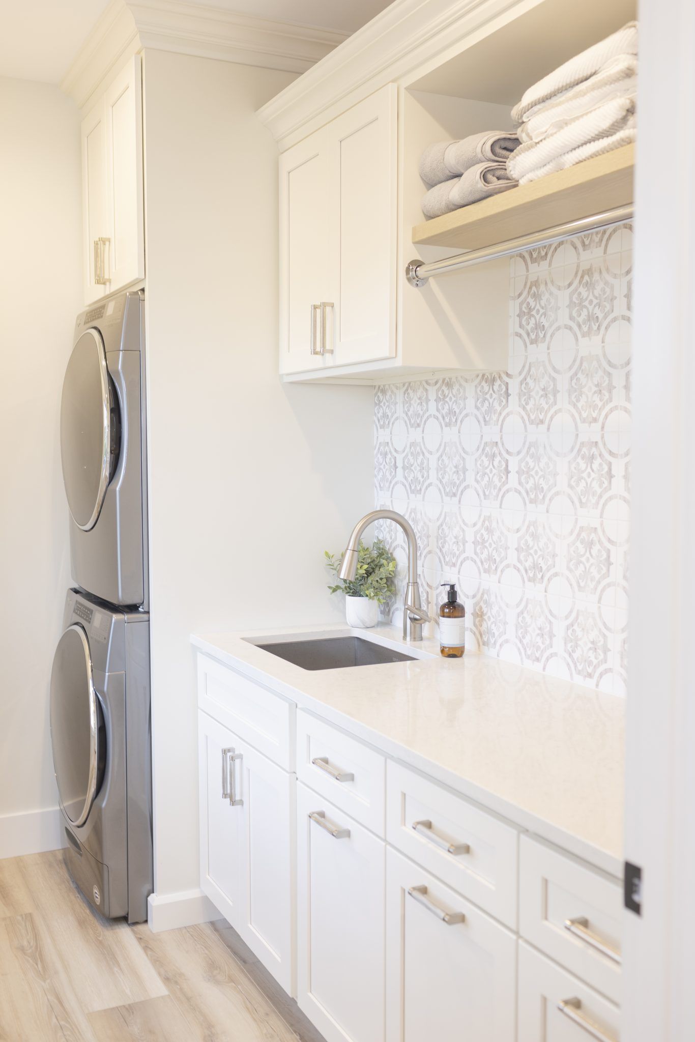 A laundry room with a washer and dryer stacked on top of each other and a sink.