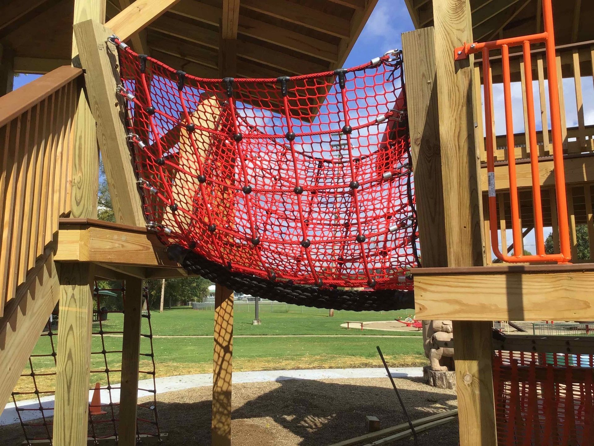 A red and black net is hanging from a wooden structure.