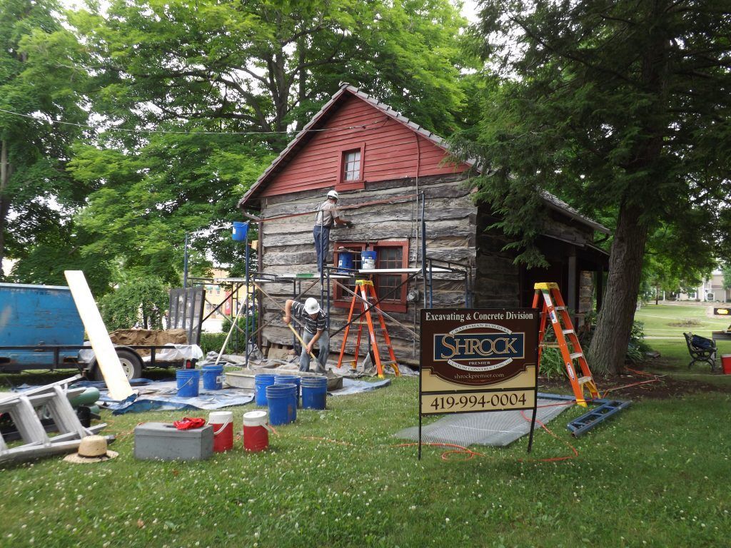 A group of people are working on a log cabin.