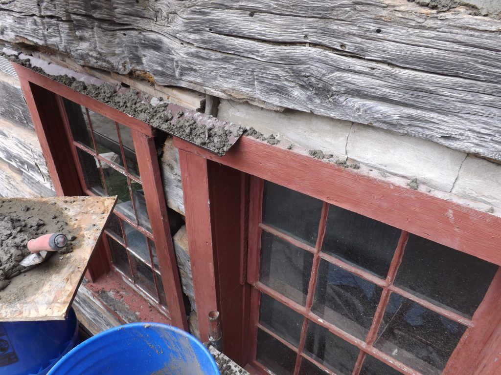 A blue bucket is sitting next to a window with a red frame.
