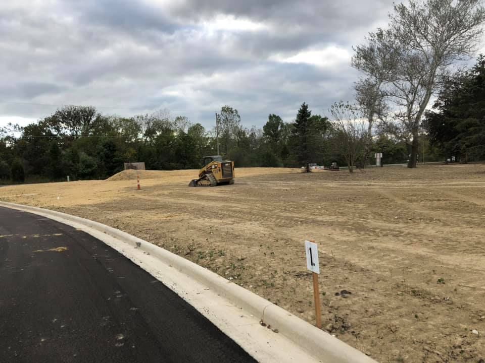 A bulldozer is working on a dirt field next to a road.