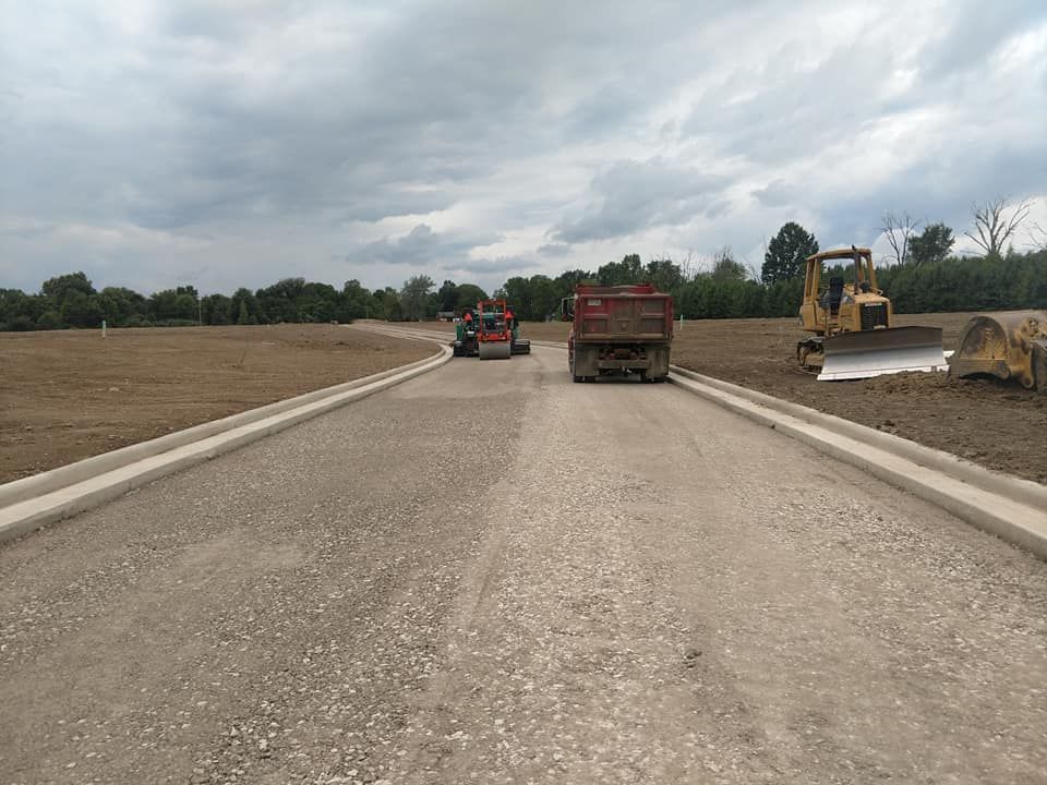 A dump truck is driving down a dirt road next to a bulldozer.