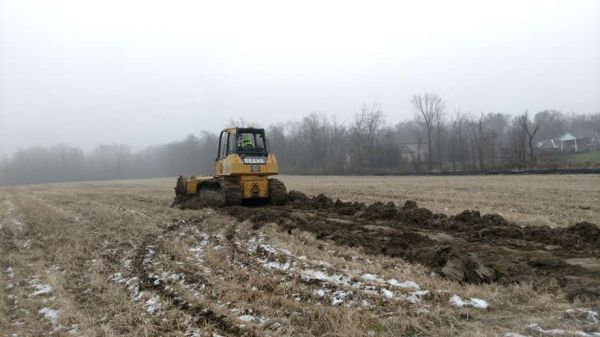 A bulldozer is plowing a field on a foggy day.