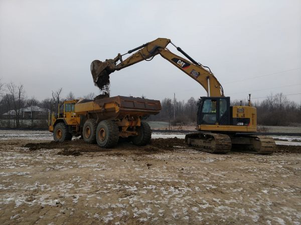 A bulldozer is loading dirt into a dump truck.