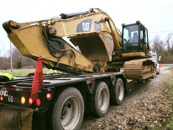 A cat excavator is being transported on a trailer.
