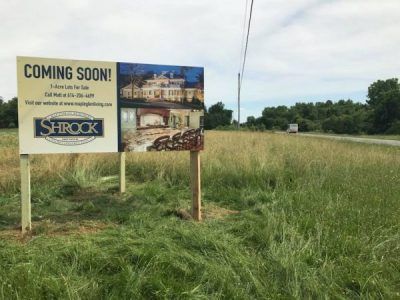 A sign in a field that says coming soon.