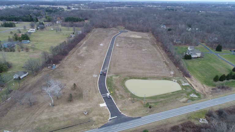 An aerial view of a residential area with a road and a pond.