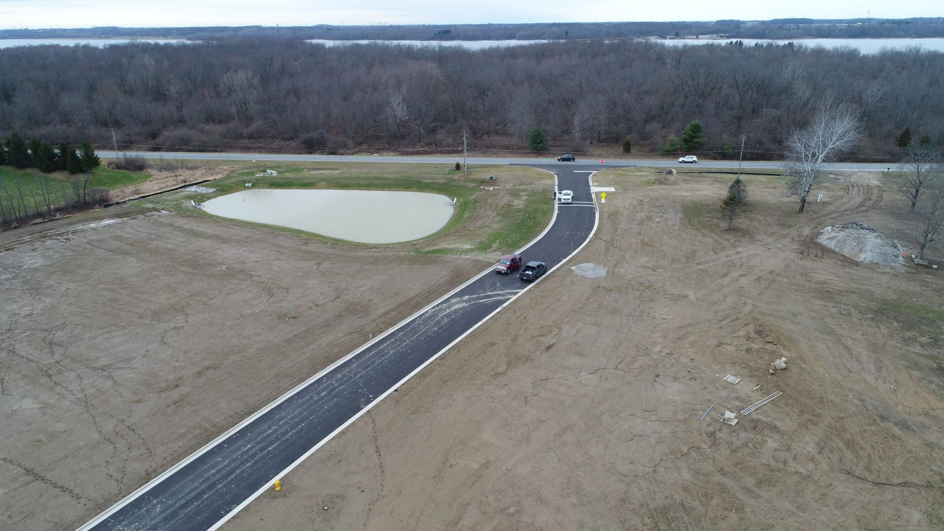 An aerial view of a road with a pond in the middle of it.