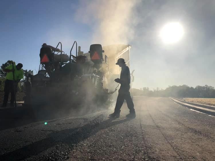 A man is walking on a road next to a machine.