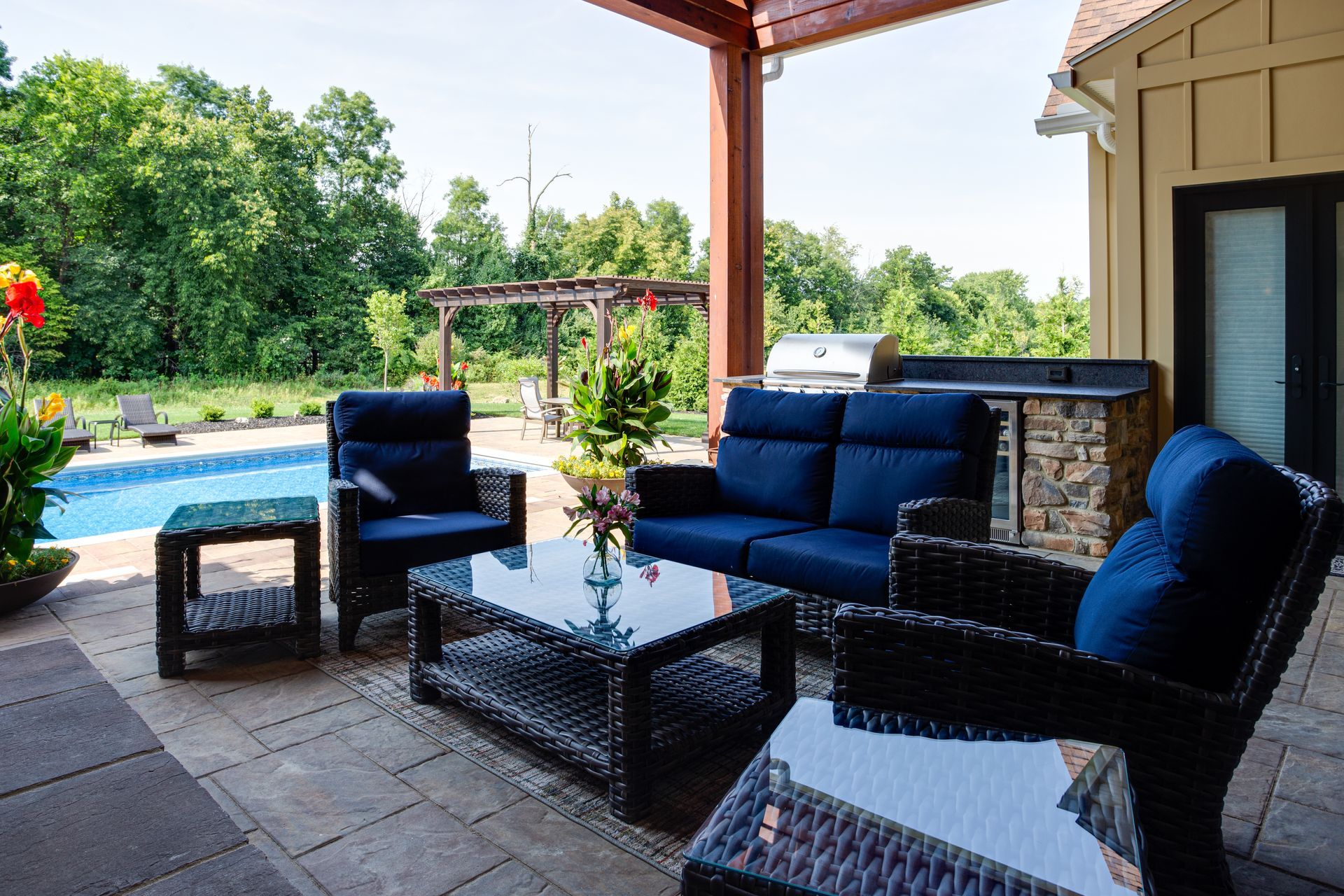 A patio with blue furniture and a swimming pool in the background.