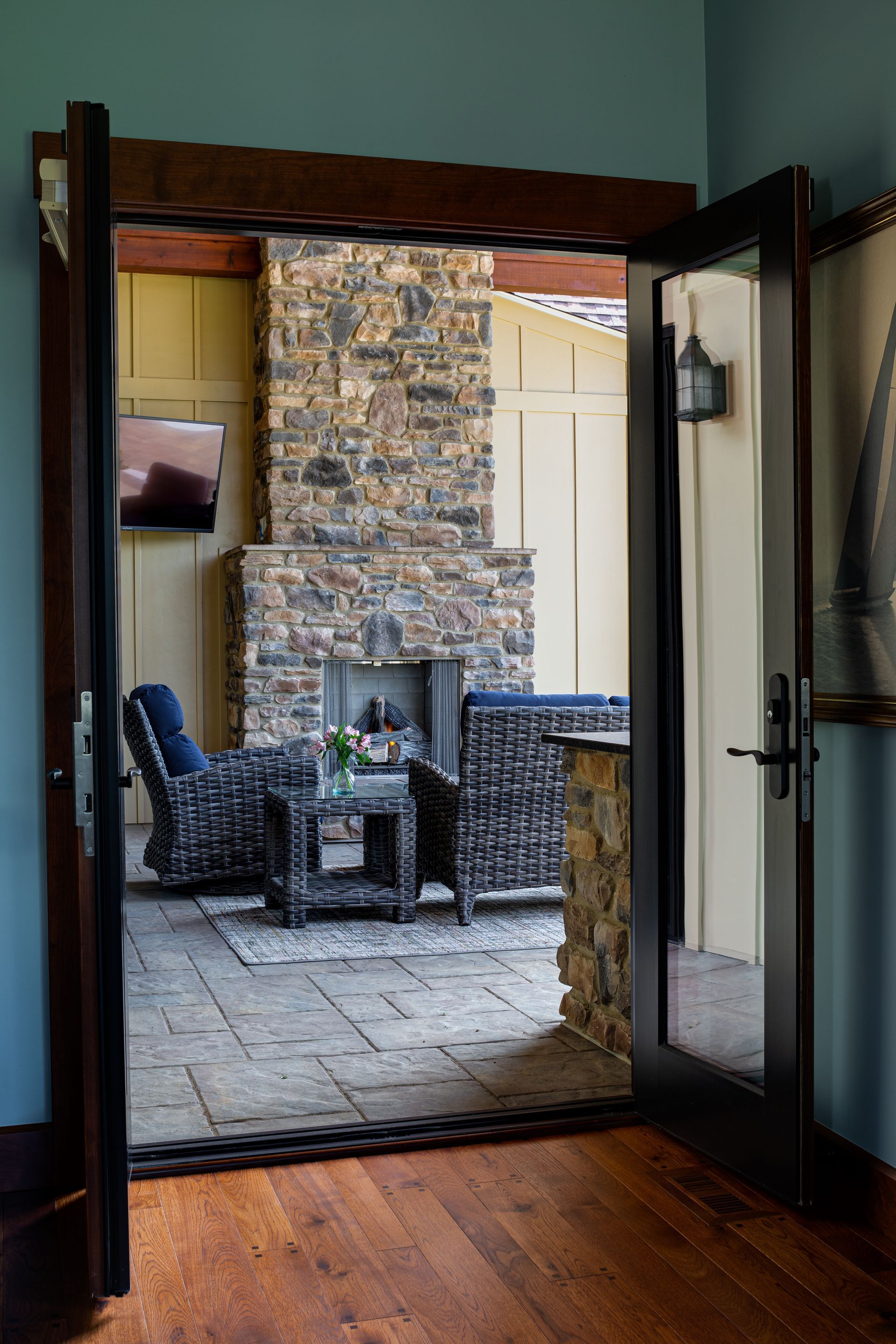 A living room with a stone fireplace and wicker furniture.