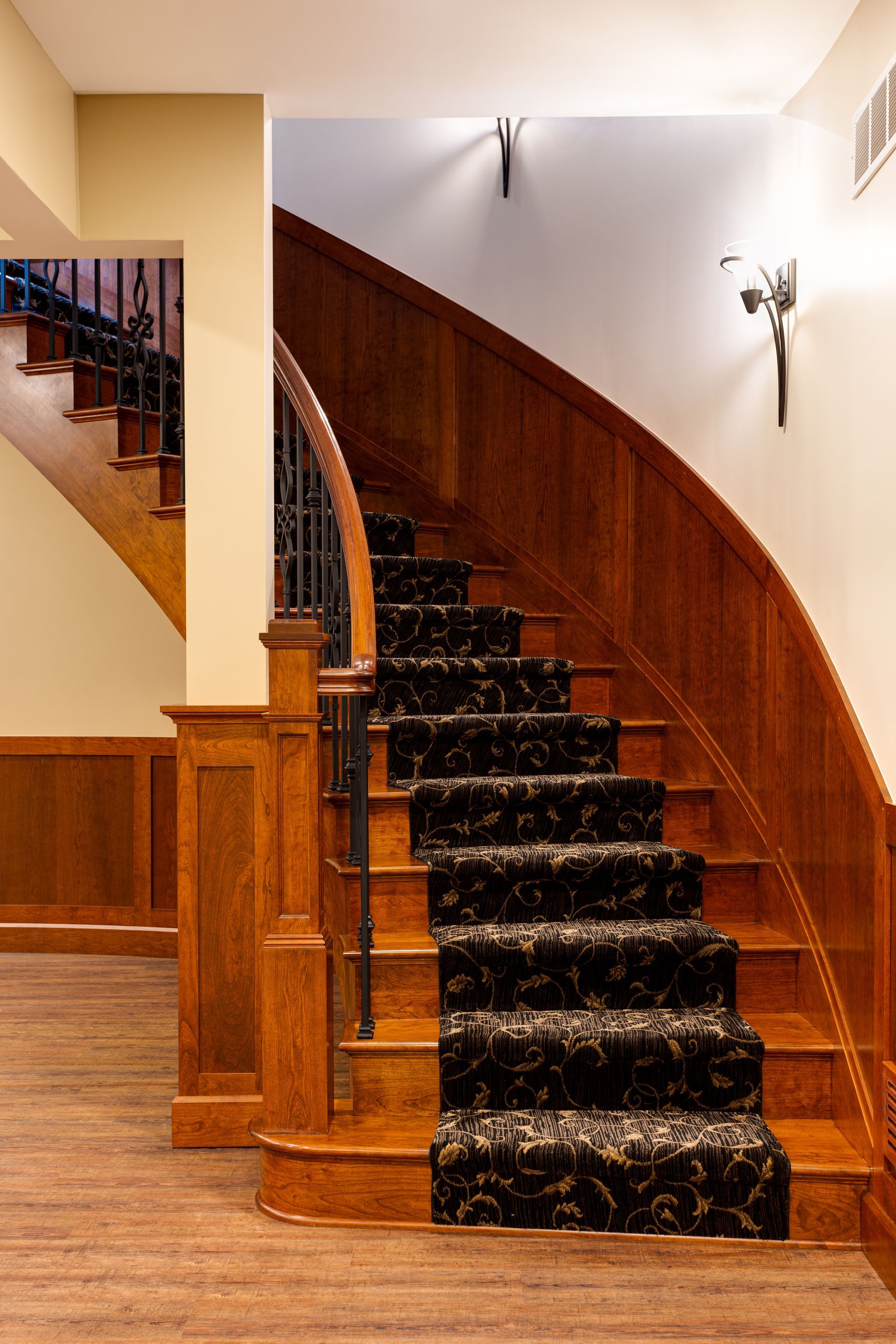 A wooden staircase with a black carpet on the steps.