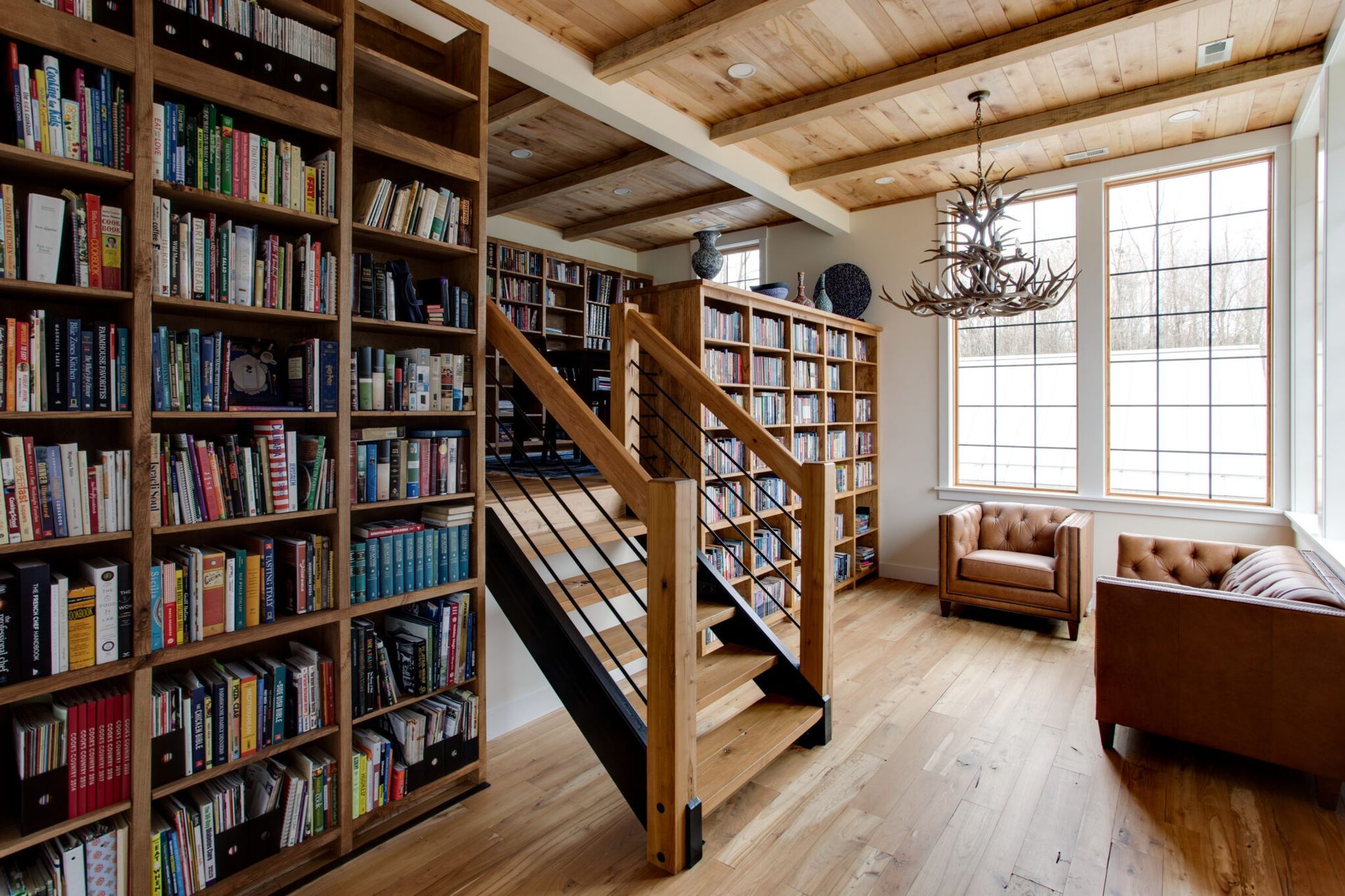 A living room filled with bookshelves and a staircase.
