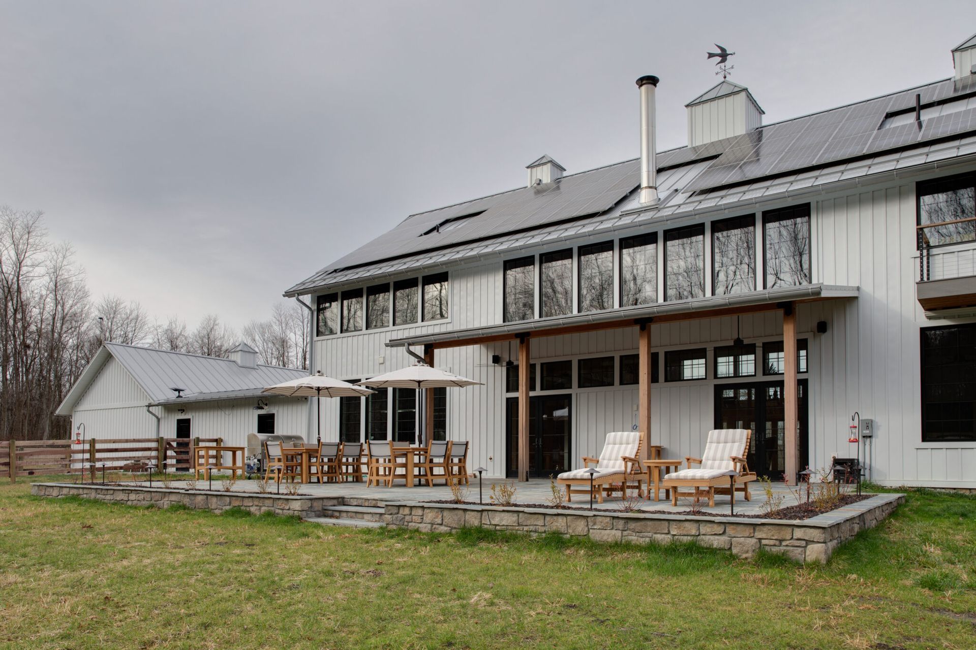 A large white house with a patio and chairs in front of it.