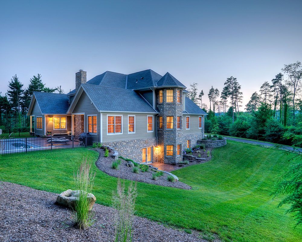 A large house sits on top of a lush green hillside