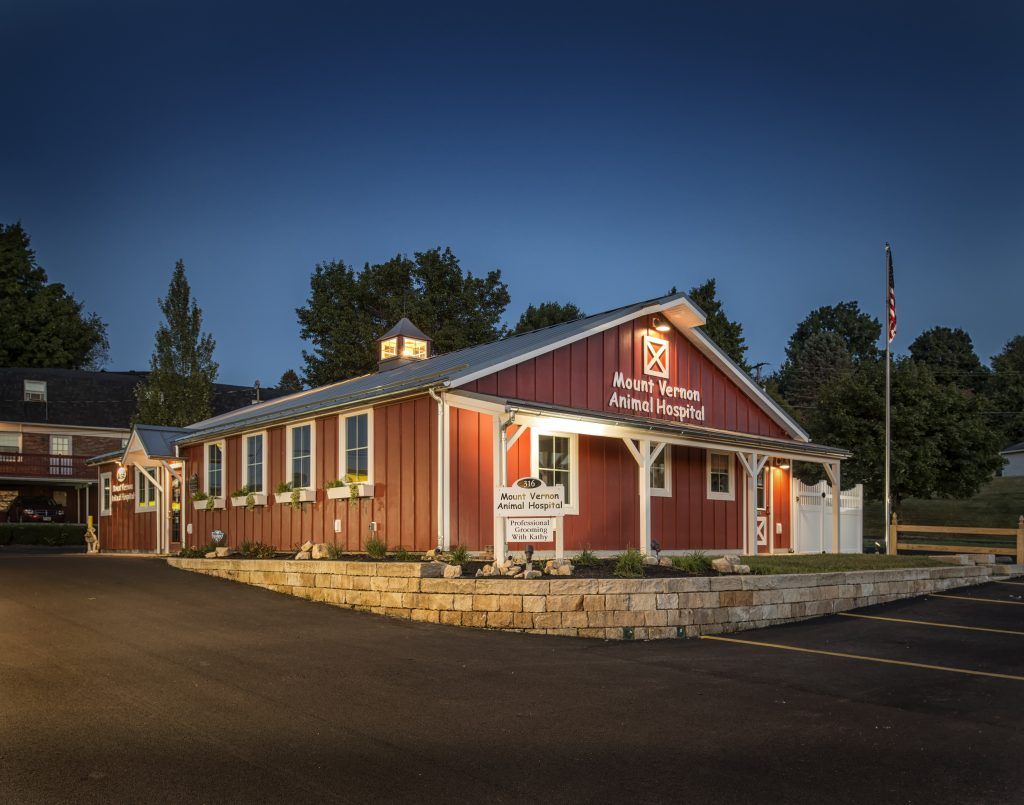 A red barn with a white roof is lit up at night