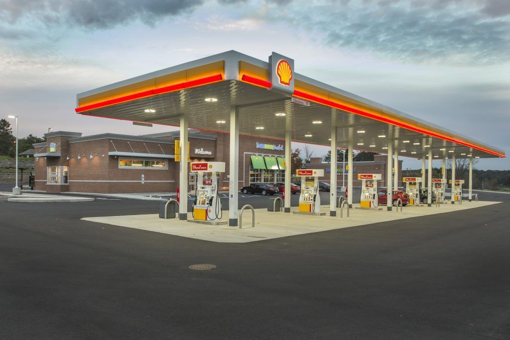 A shell gas station with cars parked in front of it.