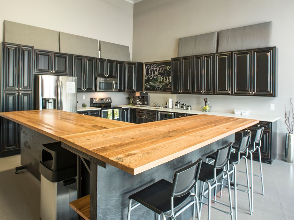 A kitchen with black cabinets and a large wooden counter top.