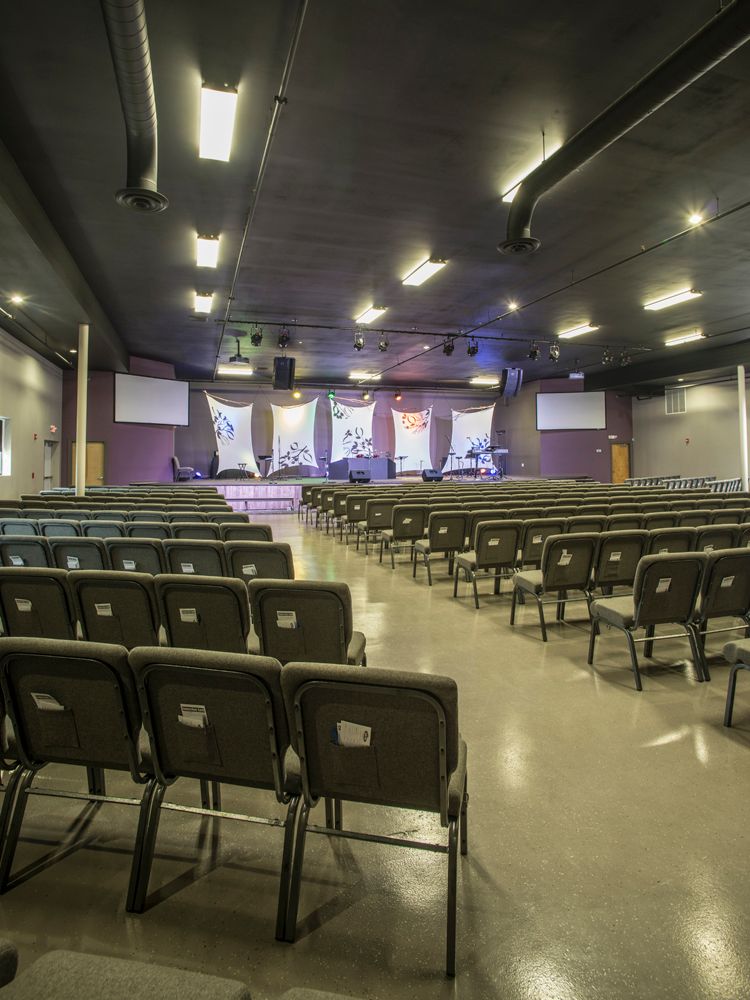 A large auditorium with rows of chairs and a stage in the background.