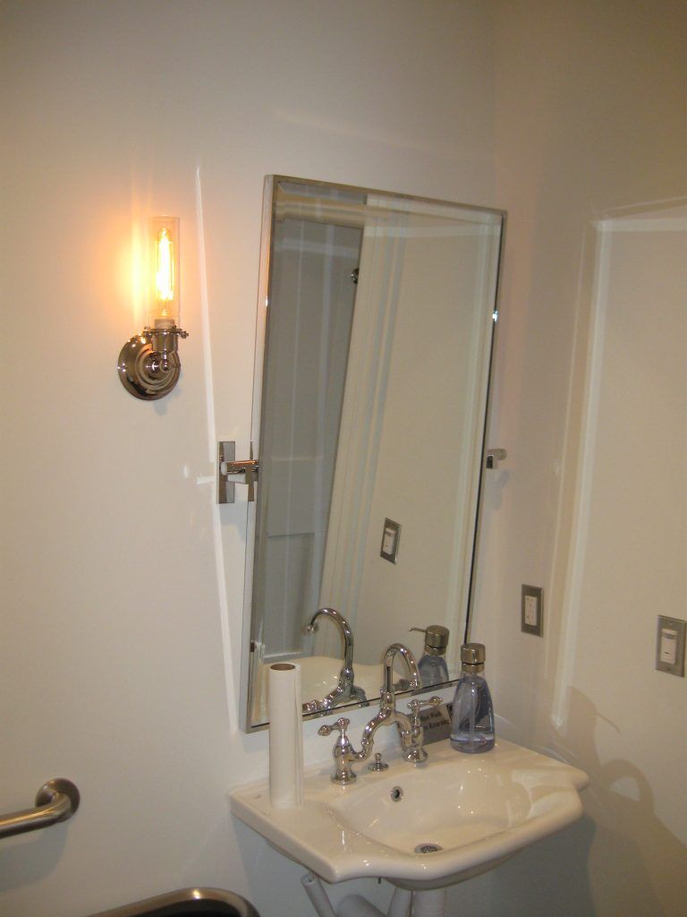 A bathroom with a sink a mirror and a light.