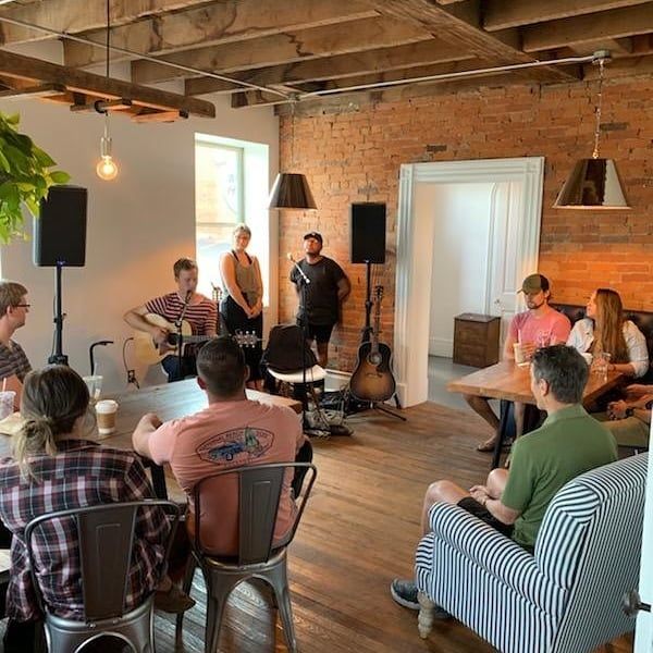 A group of people are sitting around a table in a living room.