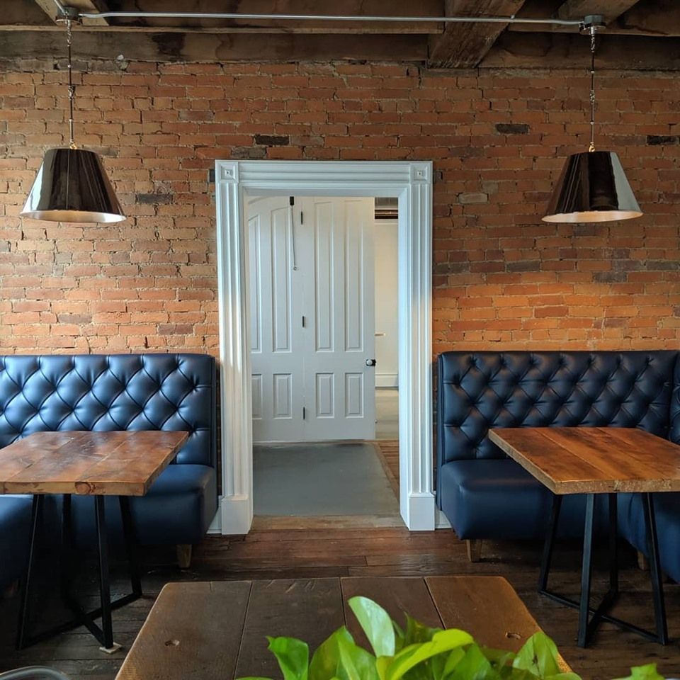 A room with a brick wall and tables and benches.