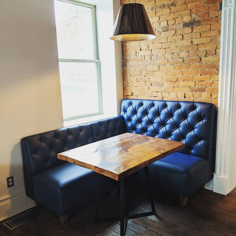 A booth with a table and chairs in front of a brick wall.
