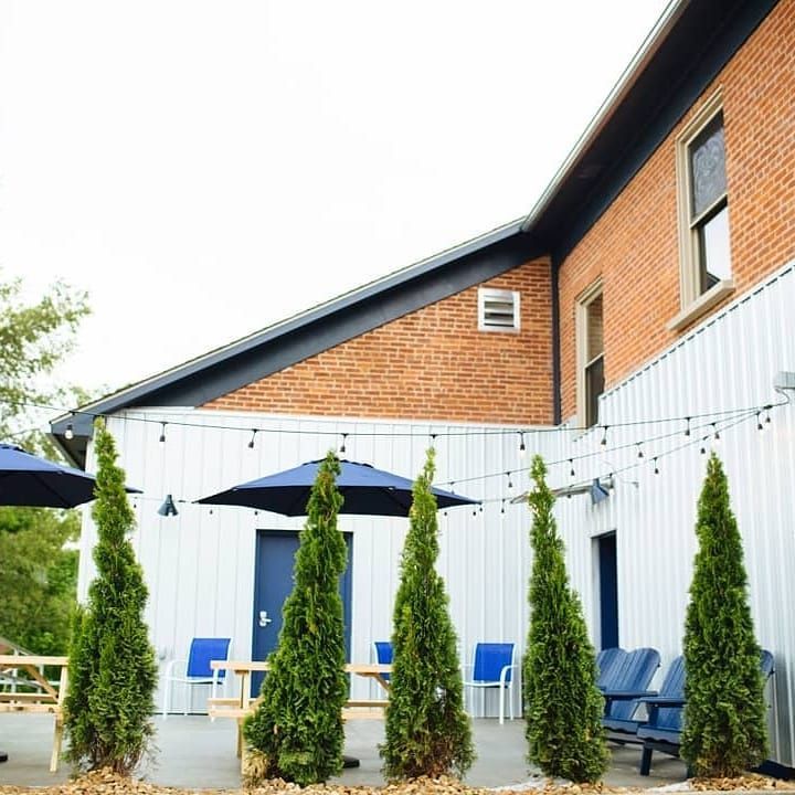 A patio with trees and umbrellas in front of a brick building.