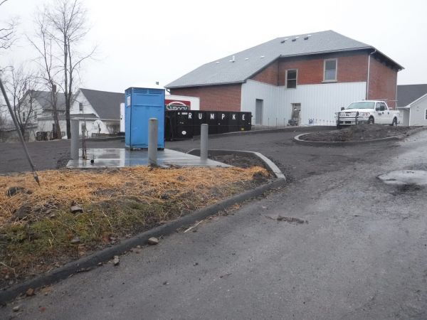 A blue portable toilet sits in front of a house.