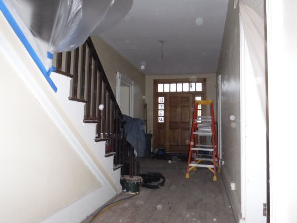 A hallway with stairs and a ladder in it.