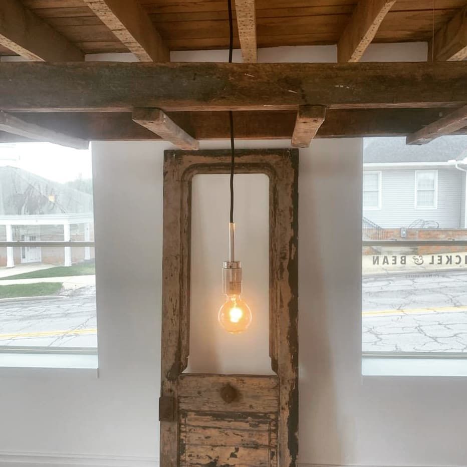 A light bulb is hanging from the ceiling above a wooden door.