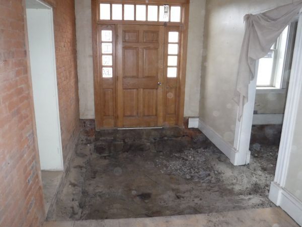 A hallway with a wooden door and a brick wall.