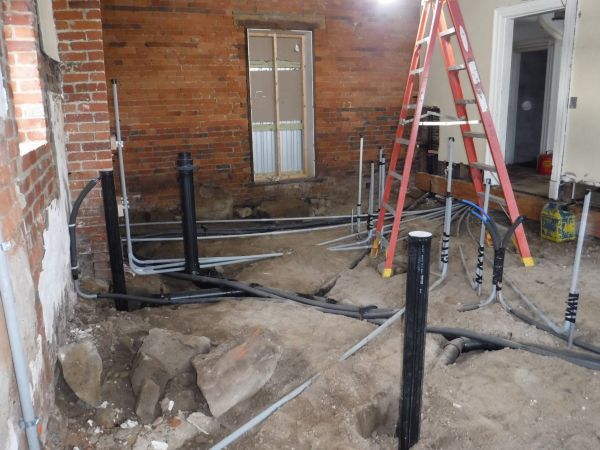 A room with a ladder and a bunch of pipes in it.