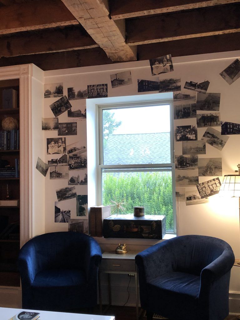 Two chairs in front of a window with pictures on the wall.