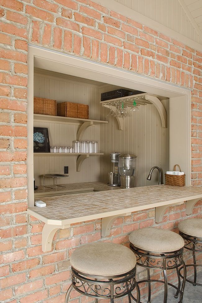 A kitchen with a brick wall and a counter and stools.