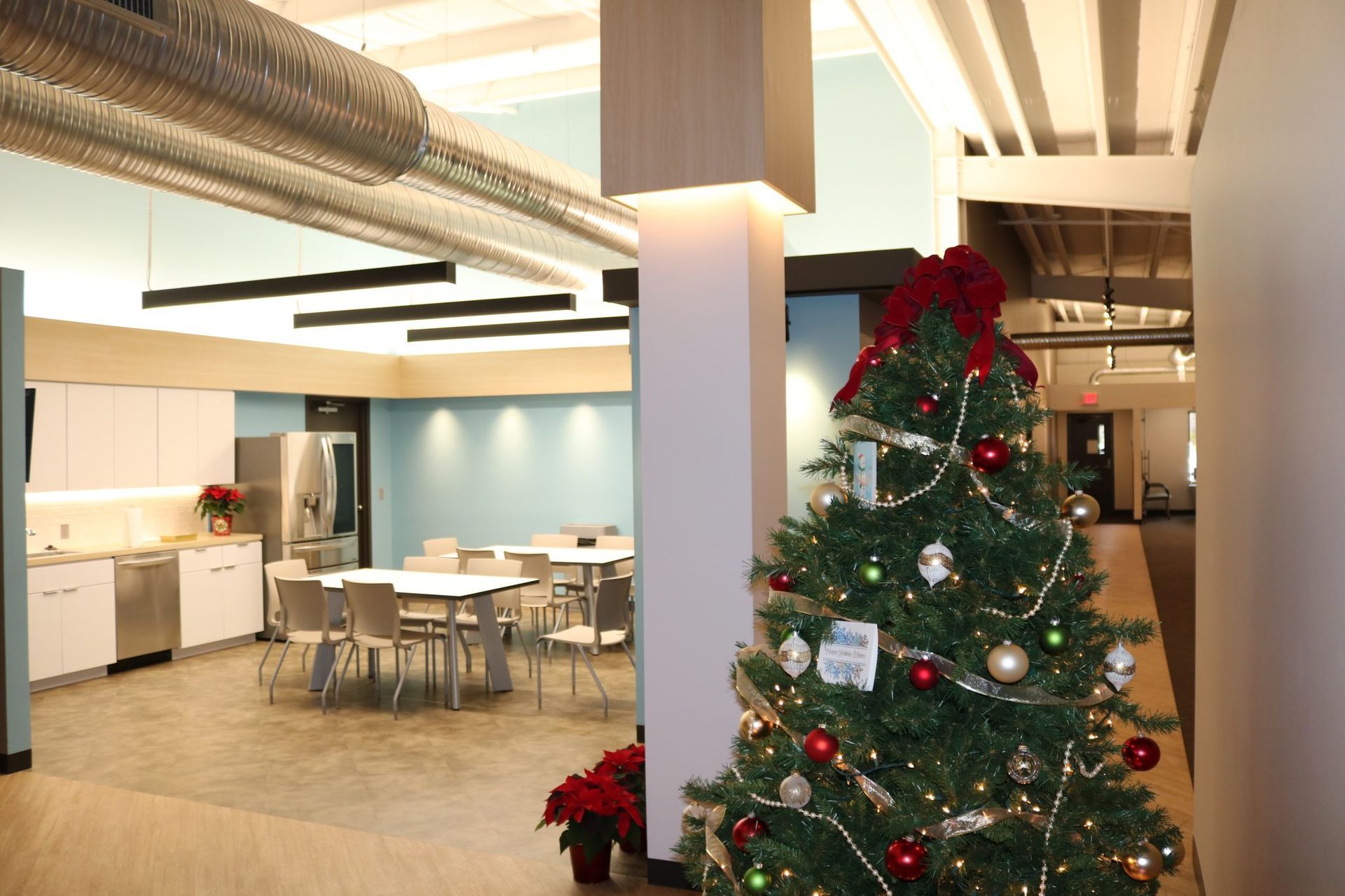 A Christmas tree in a room with tables and chairs.