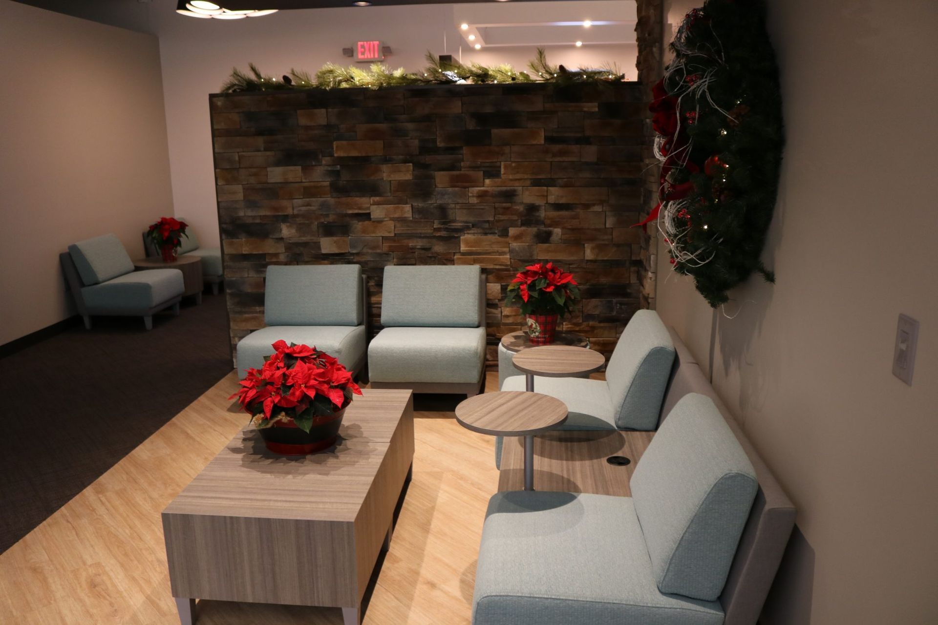 A room with chairs, a table , and a wreath on the wall.