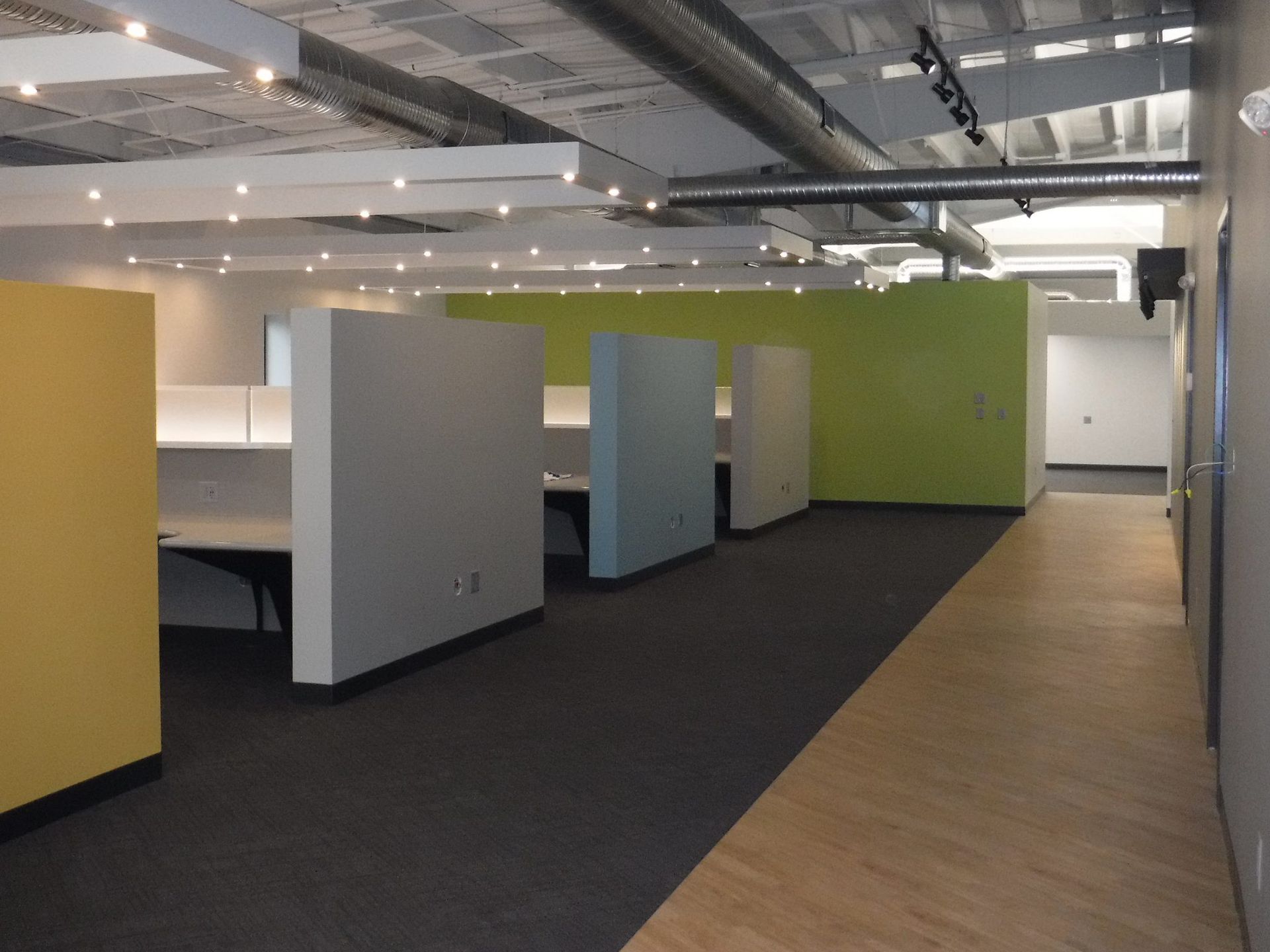 A hallway with cubicles and a green wall.