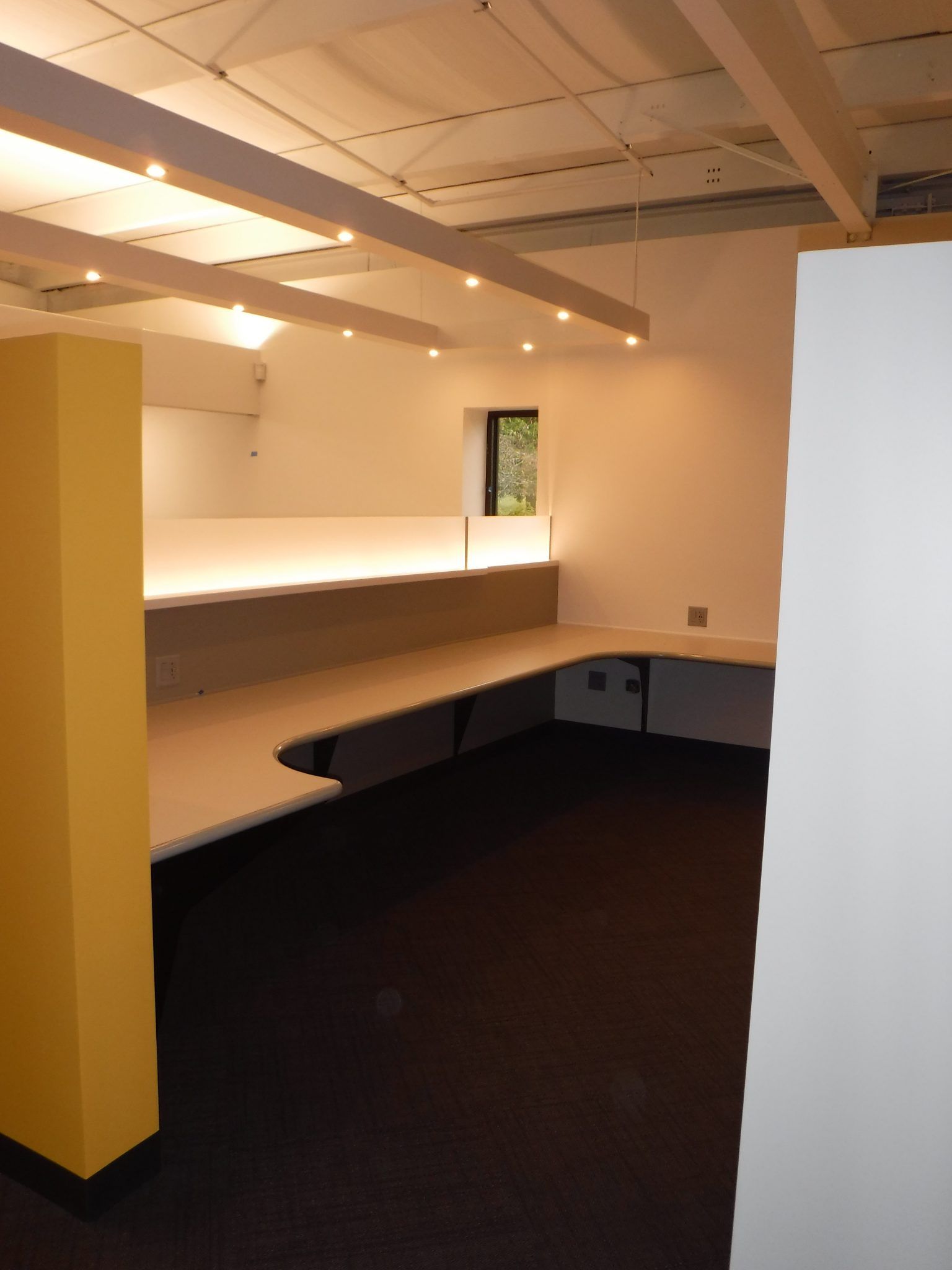 A corner of a room with a desk and a window.