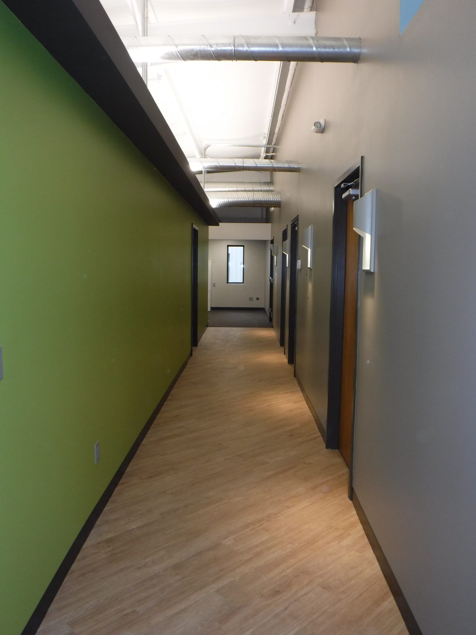 A long hallway with green walls and wood floors.