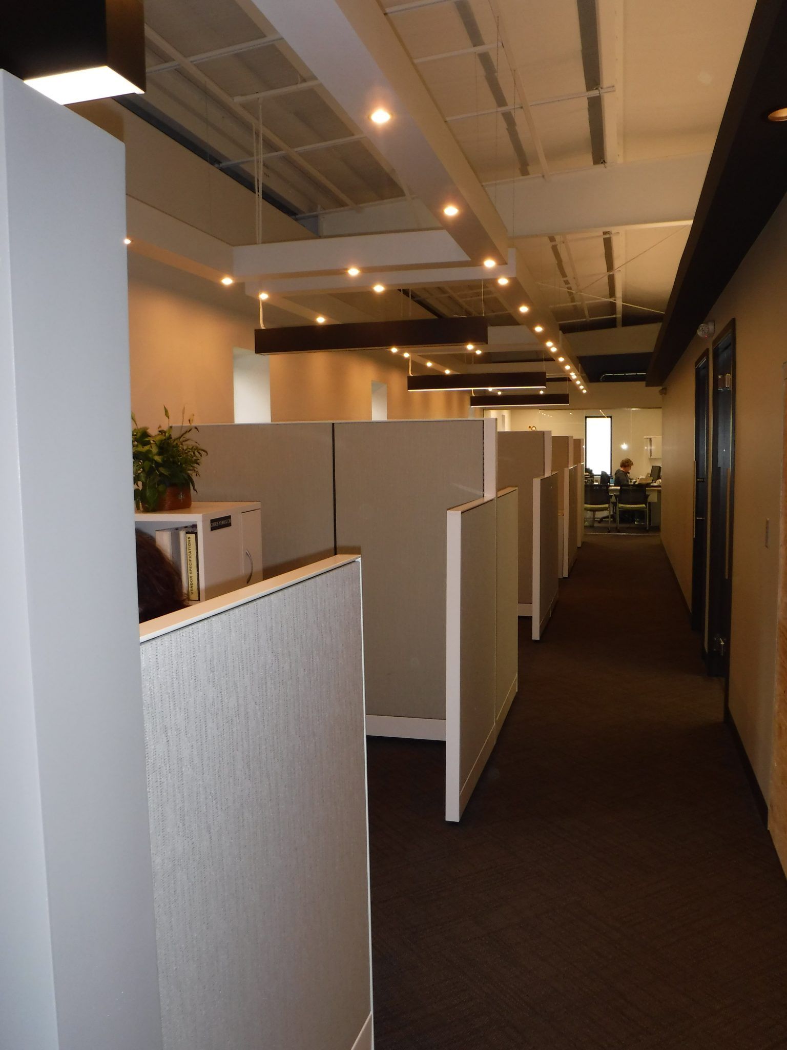 A long hallway with cubicles and rooms.