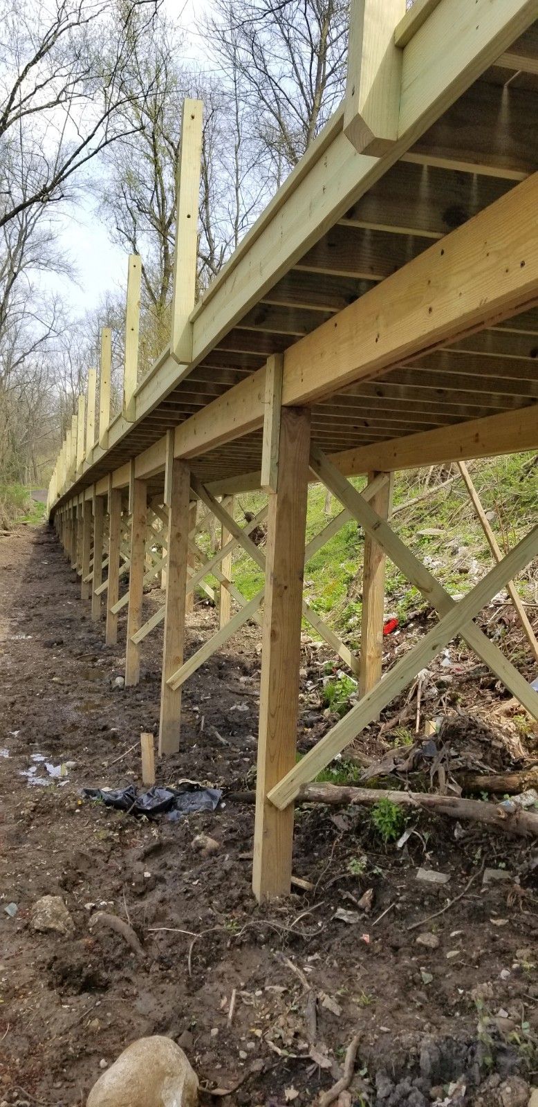 A wooden bridge is being built over a dirt path.