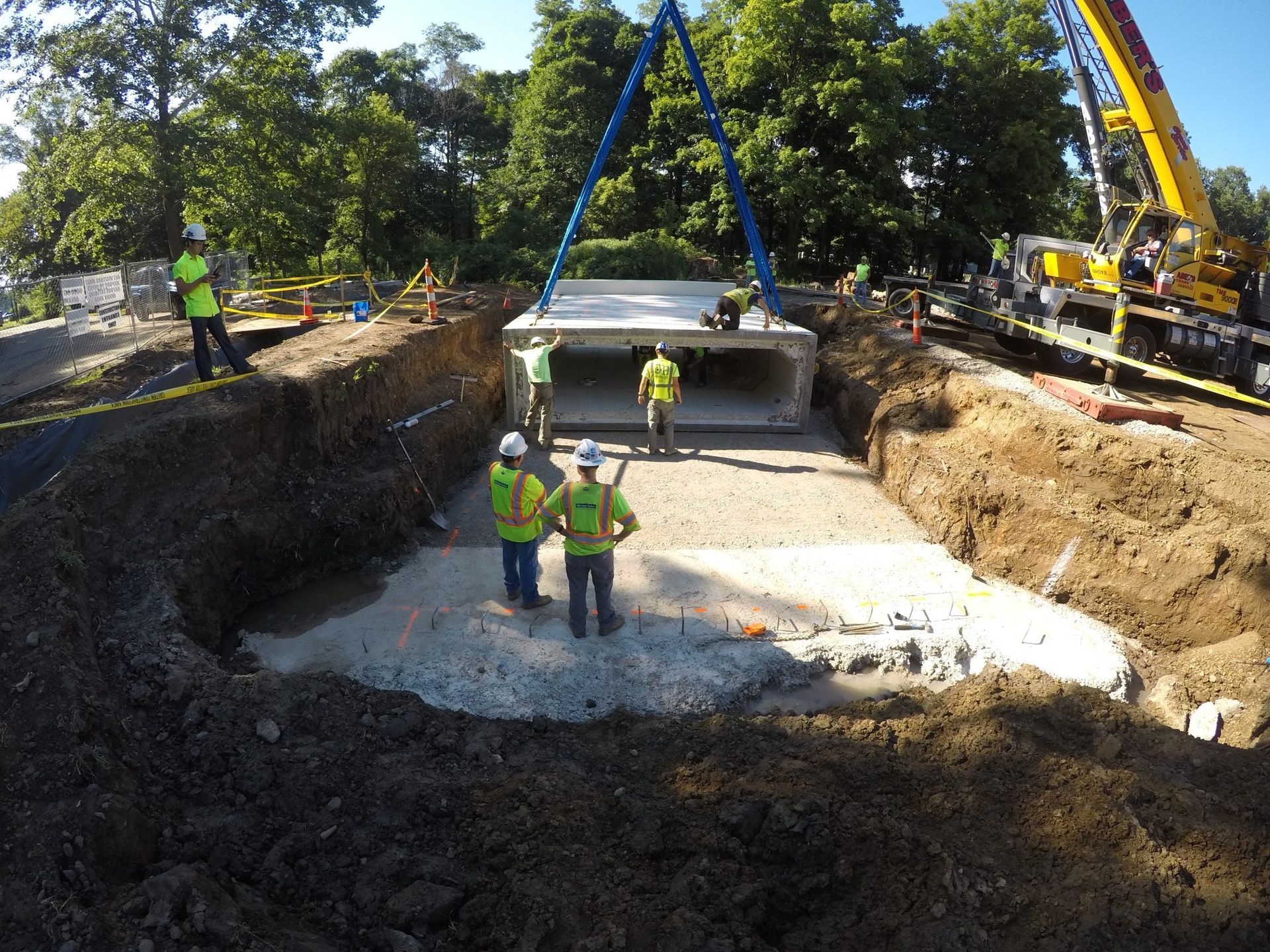 A group of construction workers are standing in a hole in the ground.
