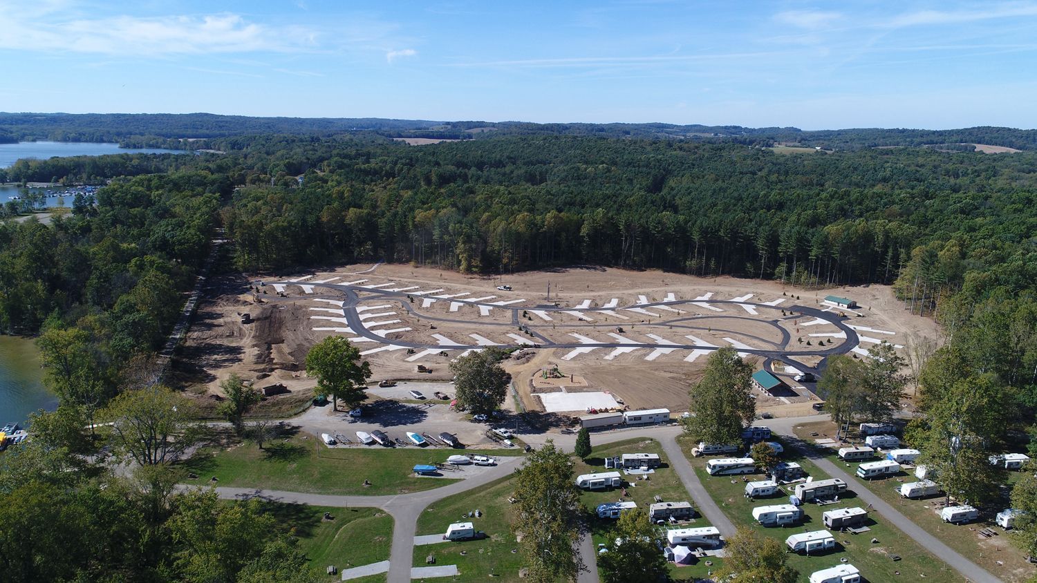 An aerial view of a campground surrounded by trees and a lake.